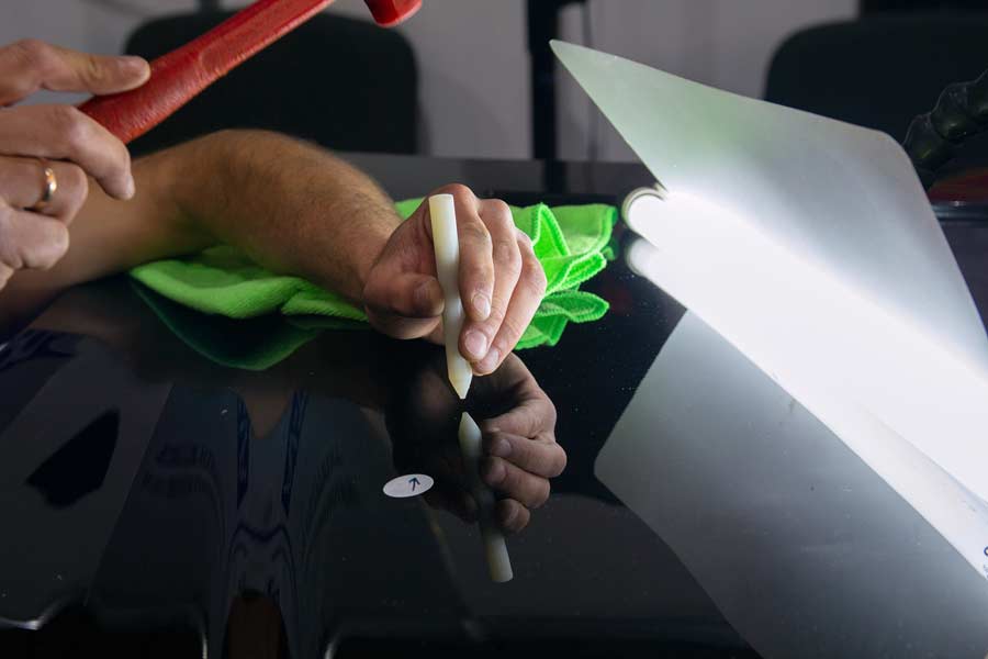 Master's hands removing dents from a car's hood