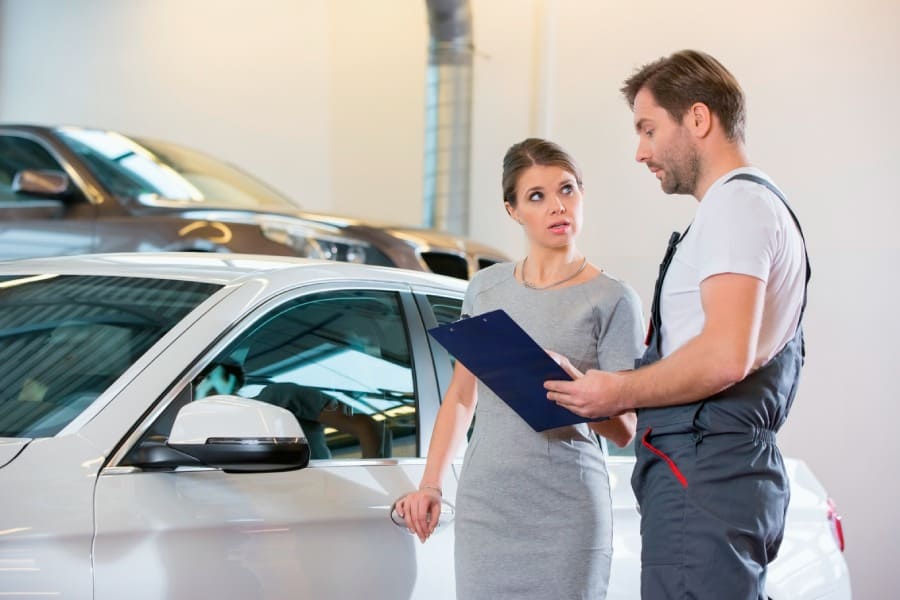 Mechanic explaining paintless car dent repair prices for auto hail damage in Austin to a client.