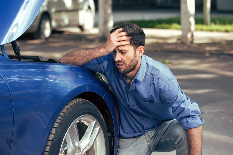 Man looking at botched DIY dent repair on his car, considering Austin paintless dent repair costs.