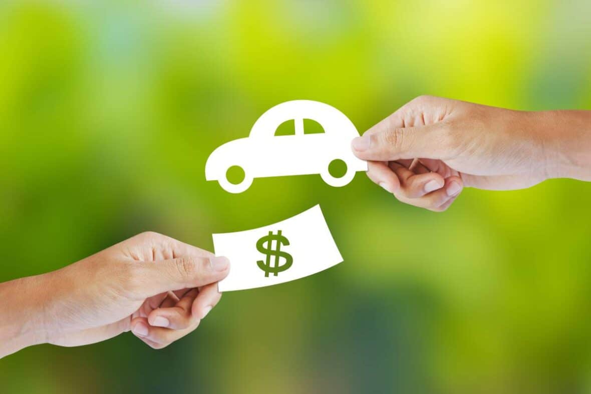 Hands holding cutouts of a car and a dollar representing paintless dent repair for hail in Austin.