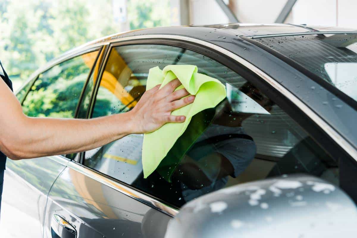 A PDR hail technician using a green cloth while performing meticulous car dent repair in Austin.