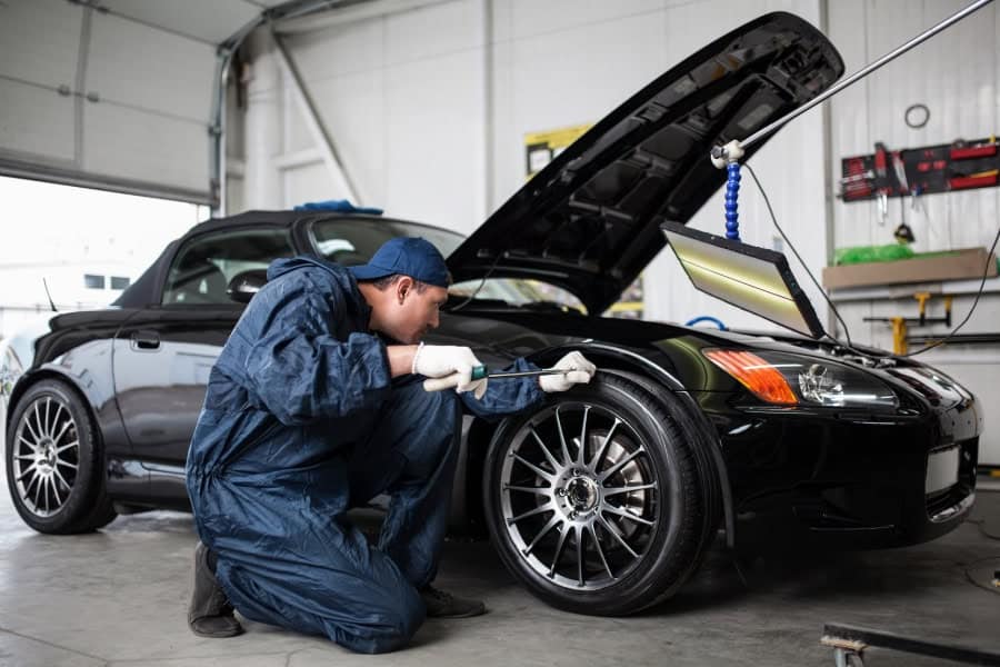 Mechanic evaluating car for Cedar Park Paintless Dent Repair estimate.