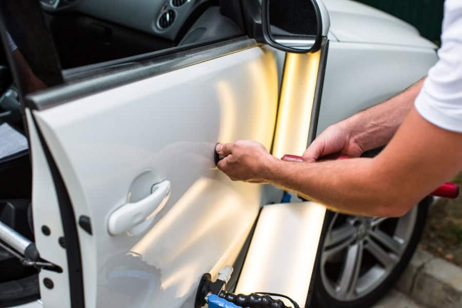 Repairing car dent after an accident. Paintless dent repair expert repairing the damaged vehicle’s door.