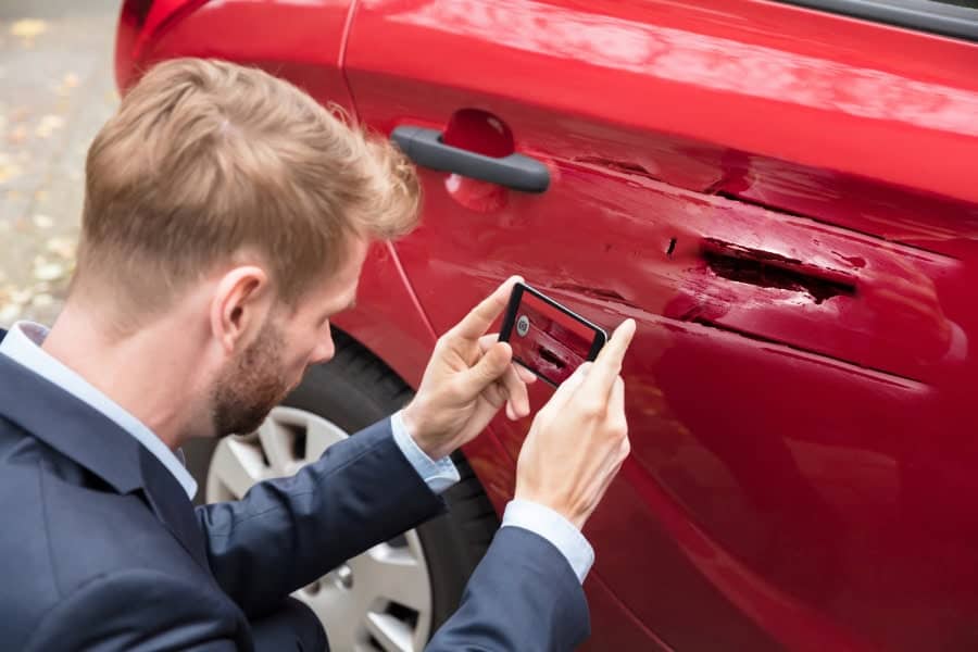 Man photographs car damage for Austin PDR assessment.