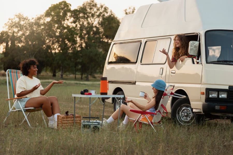 An image of a group of happy young women relaxing by their camper after dent repair in Austin TX.