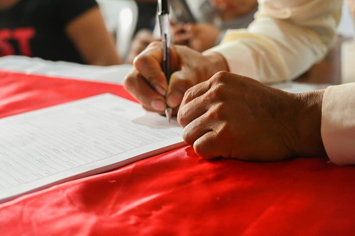 Person signing a hail damage insurance claim form for auto repair in Texas