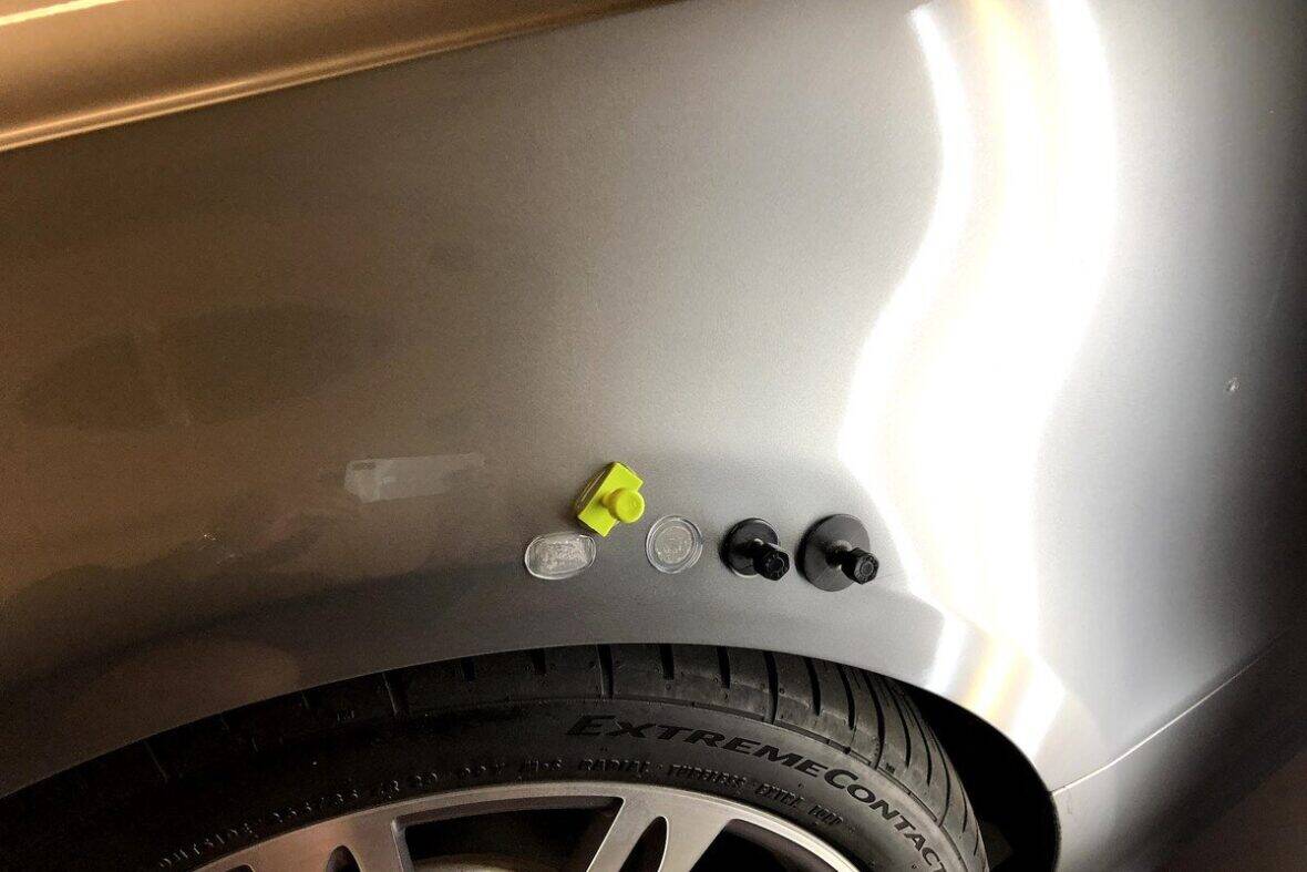 PDR technician using glue pull dent repair technique on a car panel