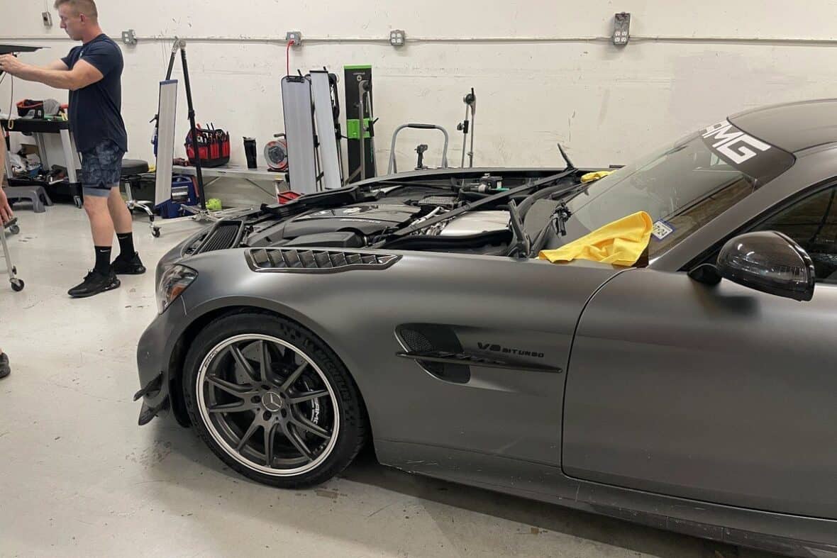 A car in a shop with its hood off getting Cedar Park dent repair